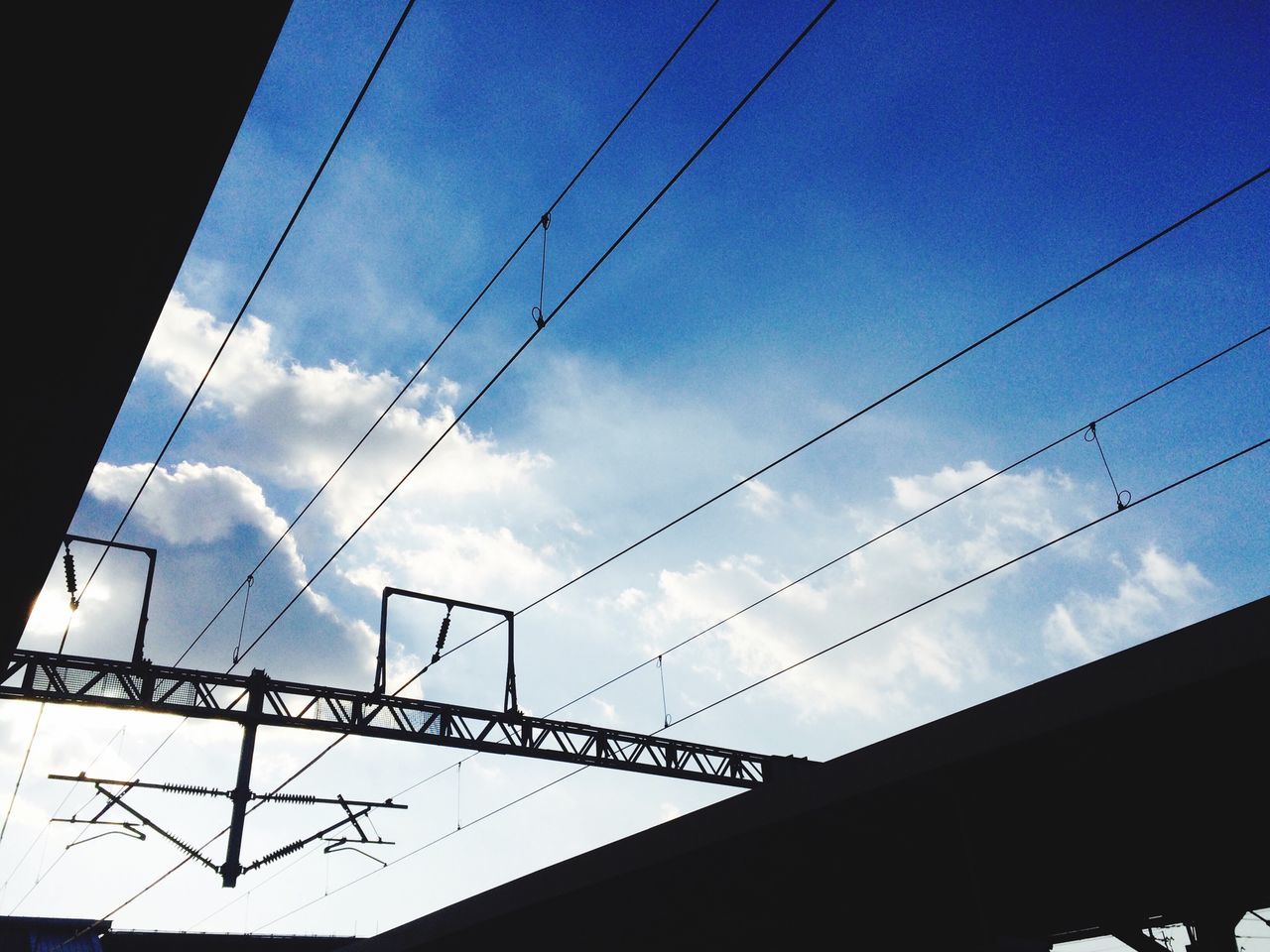 low angle view, power line, cable, connection, sky, built structure, architecture, electricity, electricity pylon, power supply, silhouette, cloud - sky, building exterior, technology, power cable, cloud, no people, dusk, outdoors, cloudy