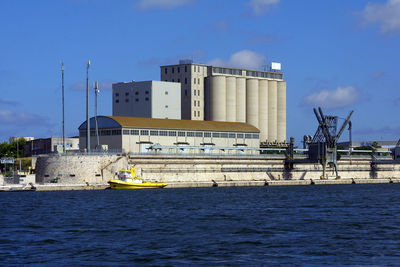 View of factory by sea against sky