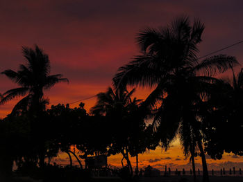 Silhouette palm trees against romantic sky at sunset