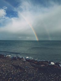 Scenic view of sea against rainbow in sky