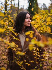 View of a pretty woman through some leaves in a forest during autumn.