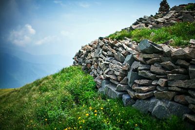 Stone stack on grassy field at mountain against sky