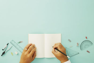 Midsection of person reading book against wall