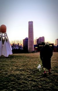 Rear view of man and cityscape against sky during sunset