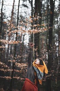 Beautiful strong asian woman dancer reaches for gold leaf in autumn