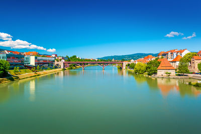 Buildings by river against clear blue sky