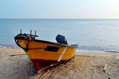 Boat moored on beach against sky