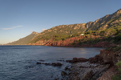 Scenic view of sea and mountains against clear sky