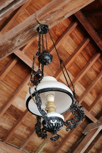 Low angle view of electric lamp hanging on ceiling in building