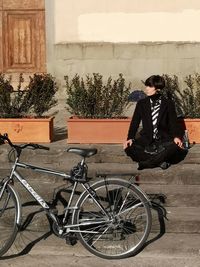 Young man sitting on bicycle against wall