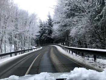 Road amidst frozen trees against sky during winter