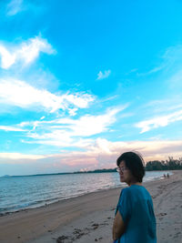 Woman standing on beach against sky