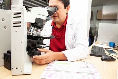 Side view of man using mobile phone while sitting on table