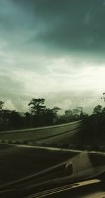 Road by trees against sky