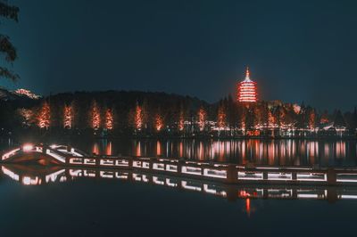 Illuminated building by river at night