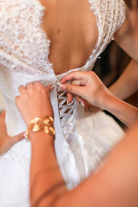 Cropped hand assisting bride for getting dressed during wedding ceremony