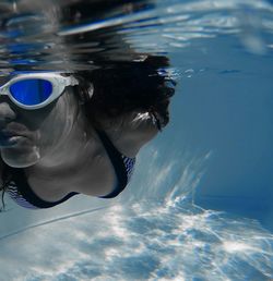 Close-up of woman with goggles swimming in pool