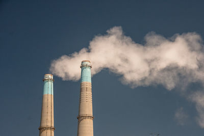 Low angle view of smoke stacks against clear sky