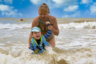 Full length of father and son on beach against sky