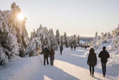 Rear view of people walking on snow covered landscape