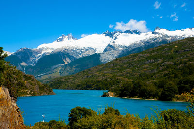 Scenic view of lake and mountains against blue sky