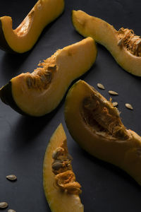 Pieces of sliced pumpkin on the dark table with dark dishes