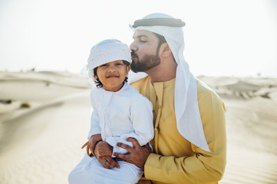 Father and son enjoying while kneeling in desert