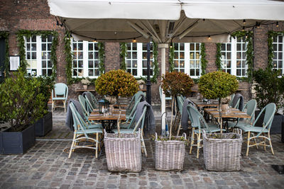 Empty chairs and tables at sidewalk cafe against building