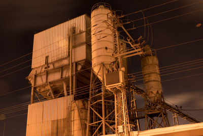 Low angle view of illuminated factory against sky at night