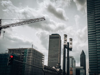 Low angle view of crane and buildings against sky
