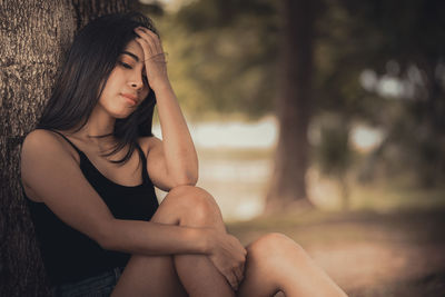 Young woman looking down while sitting outdoors