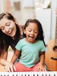 Mother and daughter playing piano at home