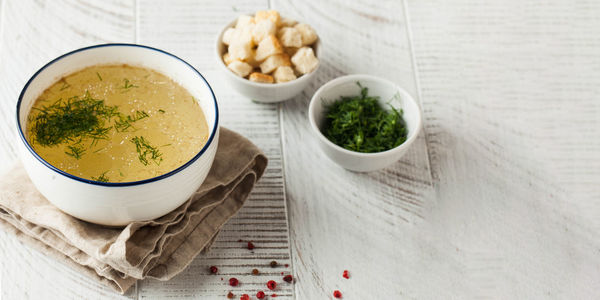 Healthy bone broth in a bowl with dill on a light wooden background. copy space