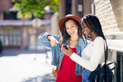 Woman showing smart phone to friend while standing outdoors