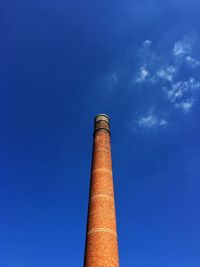 Low angle view of a brick chimney against blue sky