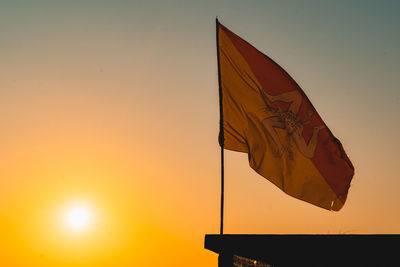 Low angle view of flag against sky during sunset