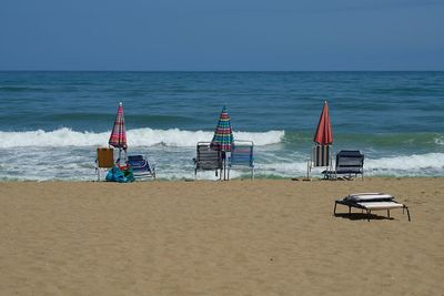 Deck chairs on beach against clear sky