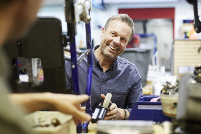 Smiling mature volunteer looking at male colleague in workshop