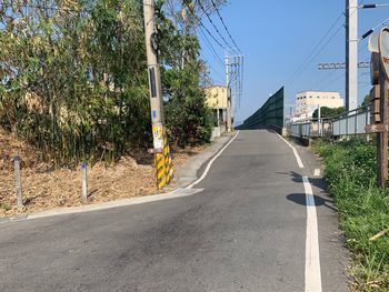 Empty road along plants and buildings