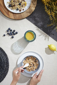 A table seen from above with a bowl of cereal with milk and orange juice