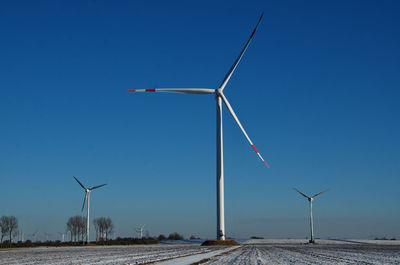 Wind turbine on field against clear blue sky