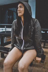 Smiling young woman looking away while sitting on bench