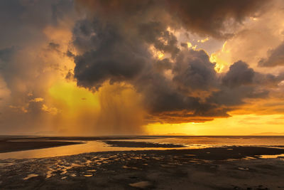 Scenic view of sea against dramatic sky during sunset