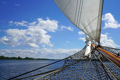 Cropped boat sailing on river against blue sky