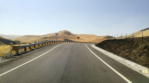 Road leading towards mountain against clear sky