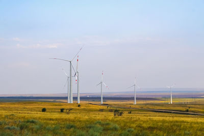 Wind turbines on field against sky