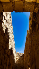 Low angle view of stone wall against clear blue sky