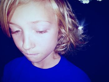 Close-up portrait of beautiful young woman against black background