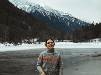 Portrait of woman standing on snowcapped mountains during winter