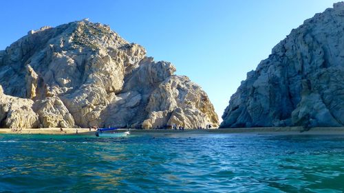 Scenic view of rocks in sea against clear blue sky